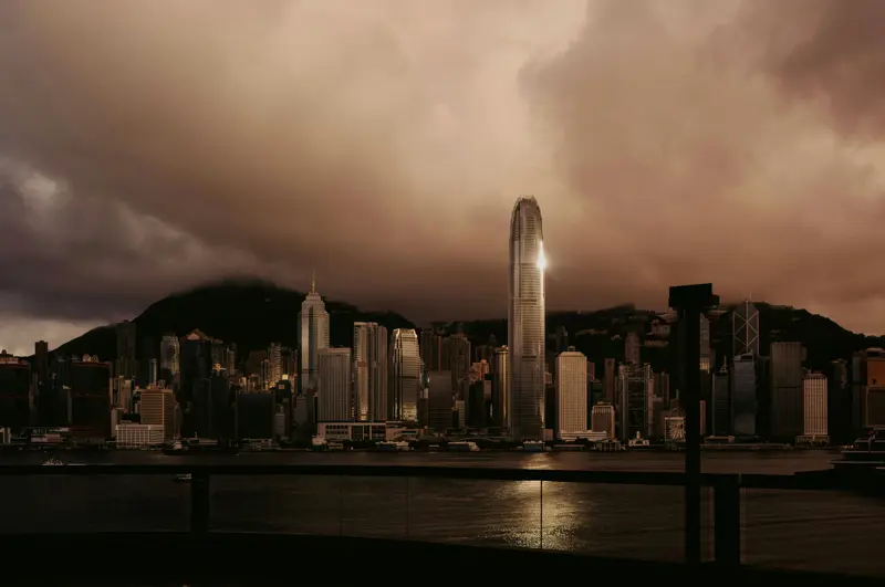 Hongkongs skyline med høye skyskrapere reflektert over Victoria Harbour i skumringen