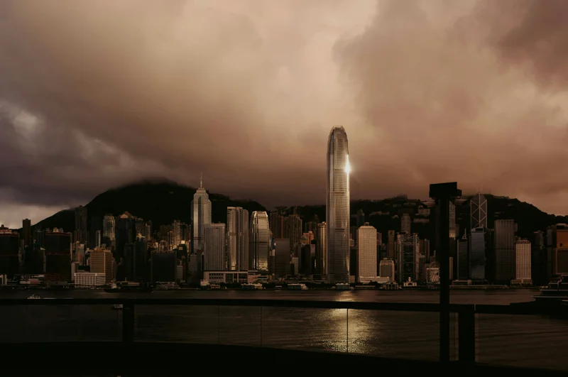 Hongkongs skyline med høye skyskrapere reflektert over Victoria Harbour i skumringen